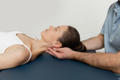 Female patient receiving osteopathic neck and shoulder treatment. therapist manipulating back head