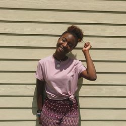 Portrait of a smiling young woman standing against shutter