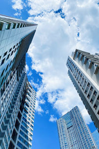 Low angle view of modern buildings against cloudy sky