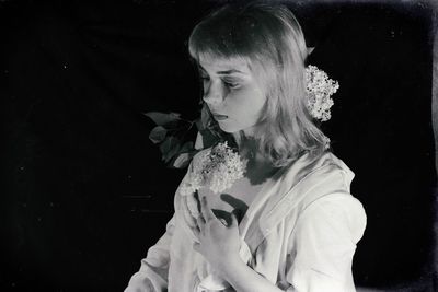 Rear view of woman looking at camera against black background