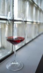 Close-up of wine in glass against industrial windows 