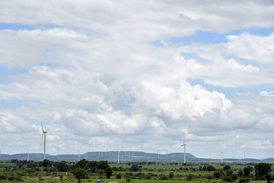 Wind turbines on landscape against sky