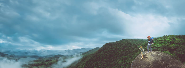 Rear view of man walking on mountain against sky