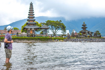 Man standing in river against temple and sky