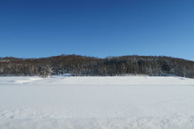 Snow covered field against clear sky