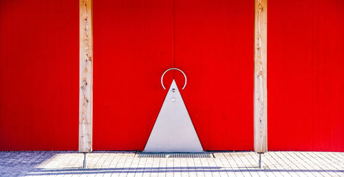 Close-up of red metal hanging against white wall