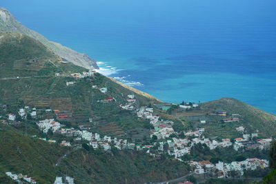 High angle view of buildings by sea against blue sky