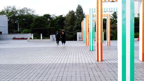 Rear view of people walking on sidewalk in city