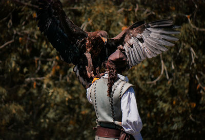 Woman standing by bird flying against blurred background