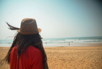 Rear view of woman on beach against sky