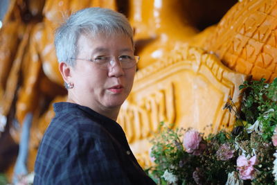 Smiling mature woman by decorated carvings at workshop