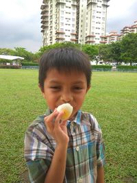 Portrait of boy holding food while standing on field