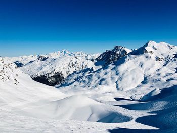 Scenic view of snowcapped mountains against clear blue sky