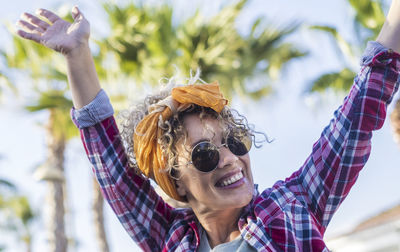 Portrait of young woman wearing sunglasses while standing against trees