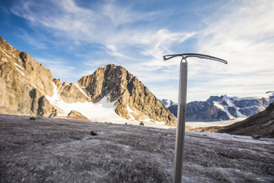 Climbers ice axe in front of glacier and mountains.