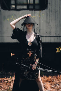 Young woman wearing hat standing against wall