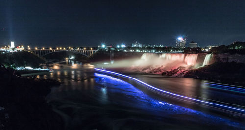 Illuminated bridge over river in city at night