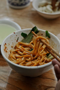 Close-up of hand holding noodles in bowl