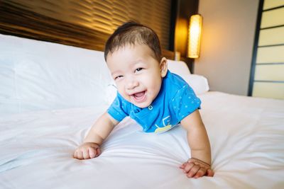 Portrait of cute boy sitting on bed at home