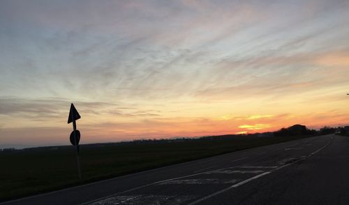 Road by street against sky during sunset