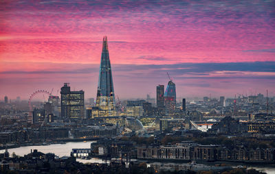 Illuminated cityscape against sky during sunset