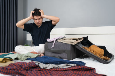 Side view of young man sitting on bed