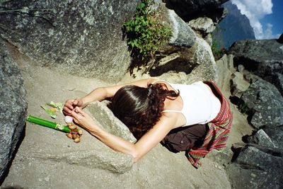 Rear view of woman meditating on rock formation at machu picchu