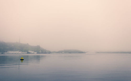 Scenic view of lake against sky during foggy weather