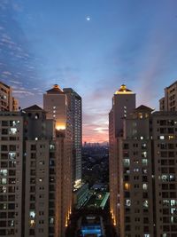 Illuminated buildings in city against sky at dusk