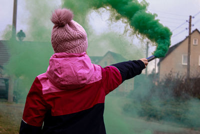Rear view of girl holding distress flare