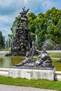 Statues at fountain with trees in background