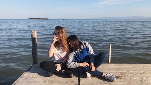 Couple sitting on shore by sea