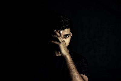 Portrait of young man against black background