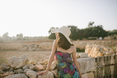 Rear view of woman on rock against sky