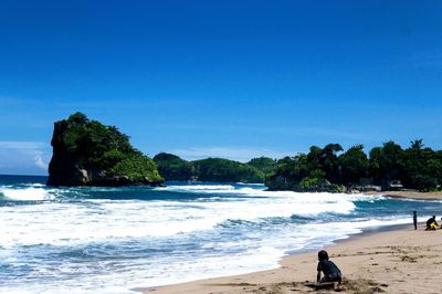 Scenic view of beach against clear blue sky