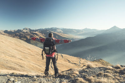 Rear view of man standing on mountain against clear blue sky