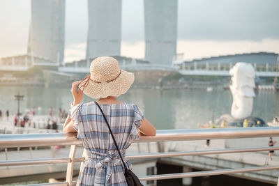 Rear view of person standing on railing against bridge