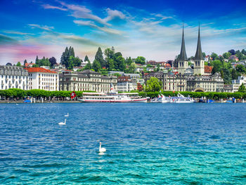 View of city at waterfront against cloudy sky