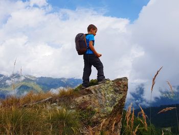 Cute boy standing on mountain against sky