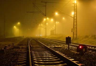 Illuminated railroad tracks against sky at night