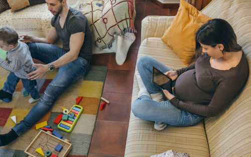 High angle view of mother using digital tablet while father and son playing at home