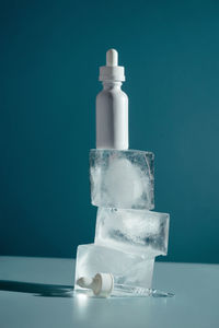 Close-up of white bottle on table against blue background