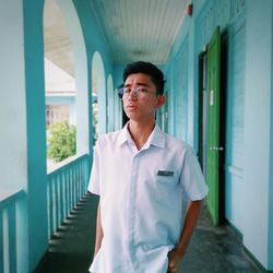 Portrait of young man standing against building