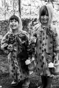 Portrait of smiling siblings in raincoat sanding outdoors