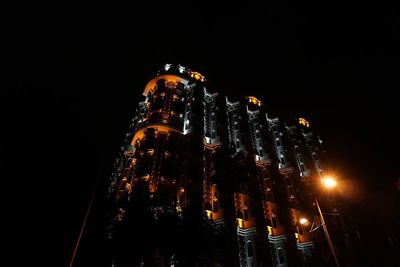 Low angle view of illuminated city against sky at night