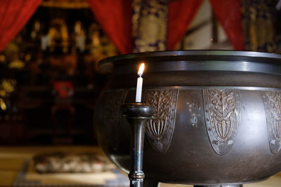 Close-up of lit candle and container in church