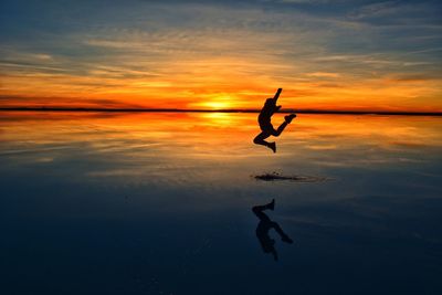 Silhouette man jumping at salar de uyuni during sky