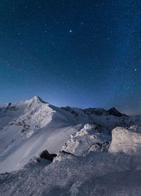 Scenic view of snowcapped mountains against sky at night