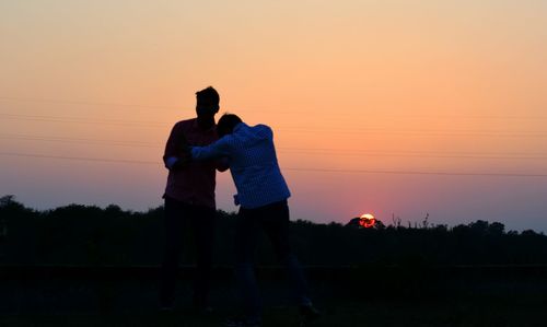 Silhouette of woman standing at sunset