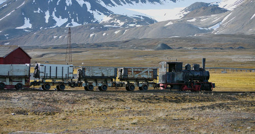 Train on field against snowcapped mountains